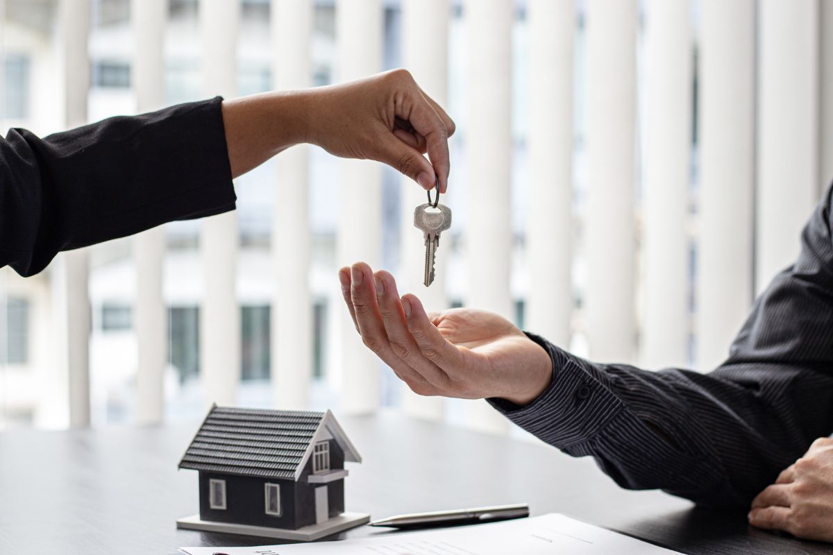 A realtor hands a new homeowner the key to their home.